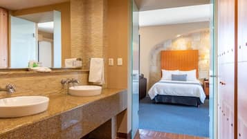 Un baño de hotel con encimera de granito, dos lavamanos y un espejo grande.