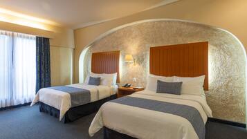 Habitación de hotel con dos camas, una pared curva y un ventanal con cortinas.