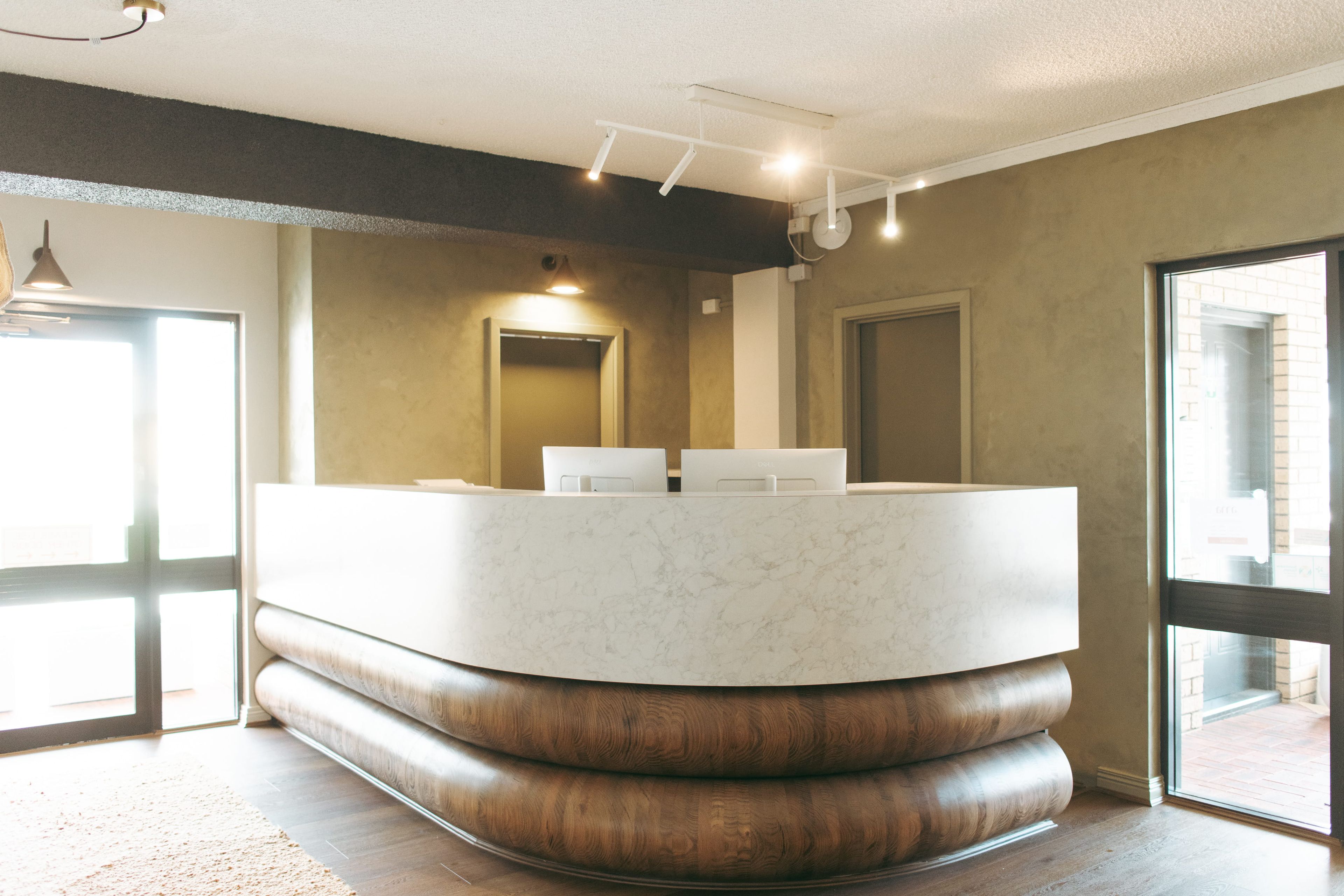 A reception desk with a marble top, wooden base, and a mirror above it.