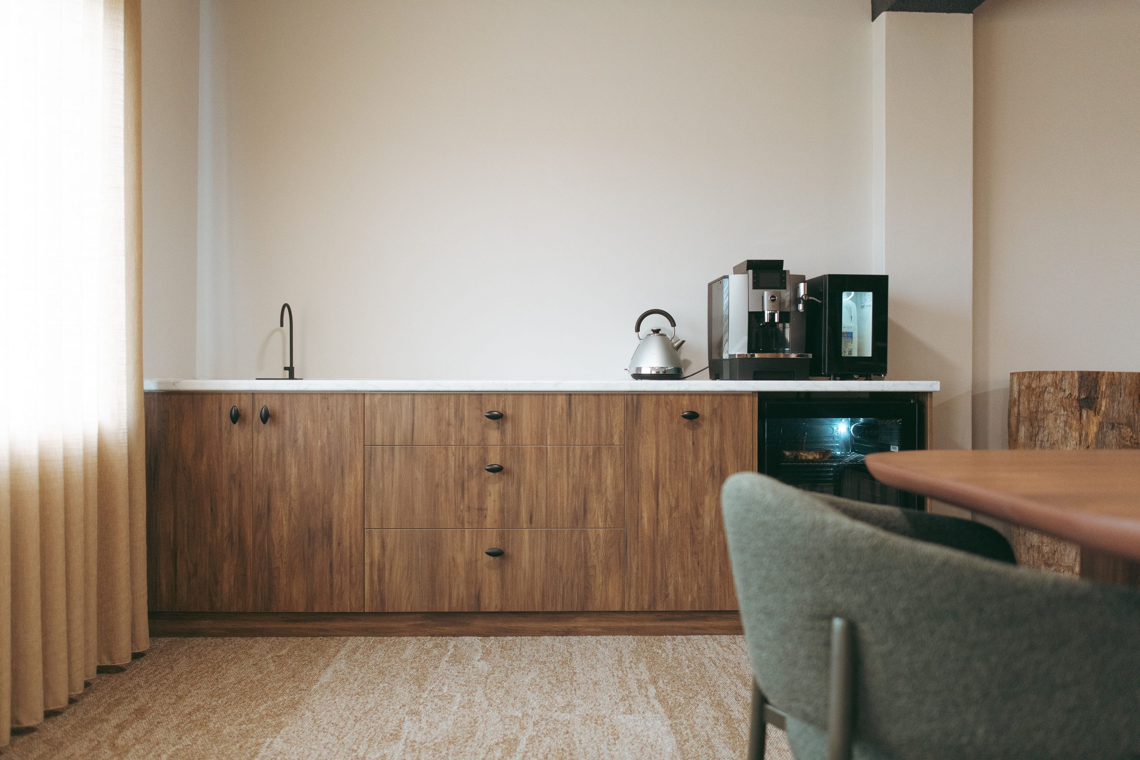 Una cocina con armarios de madera, hervidor, cafetera y microondas.