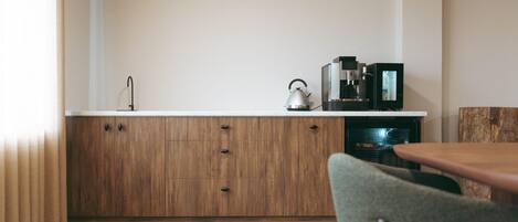 Una cocina con armarios de madera, hervidor, cafetera y microondas.