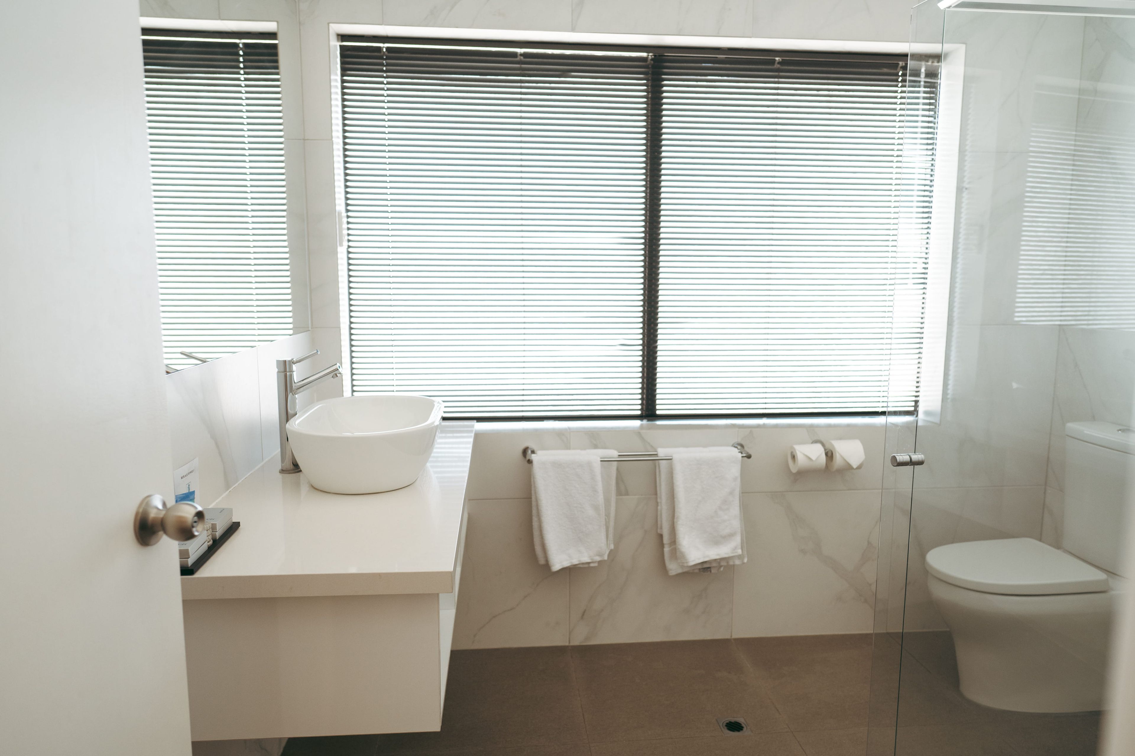 A modern bathroom with a white sink, a glass shower enclosure, and a toilet.