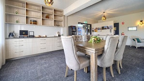A modern kitchen with a wooden table, four chairs, and a countertop with appliances. - Albany Motel & Apartments (Albany)