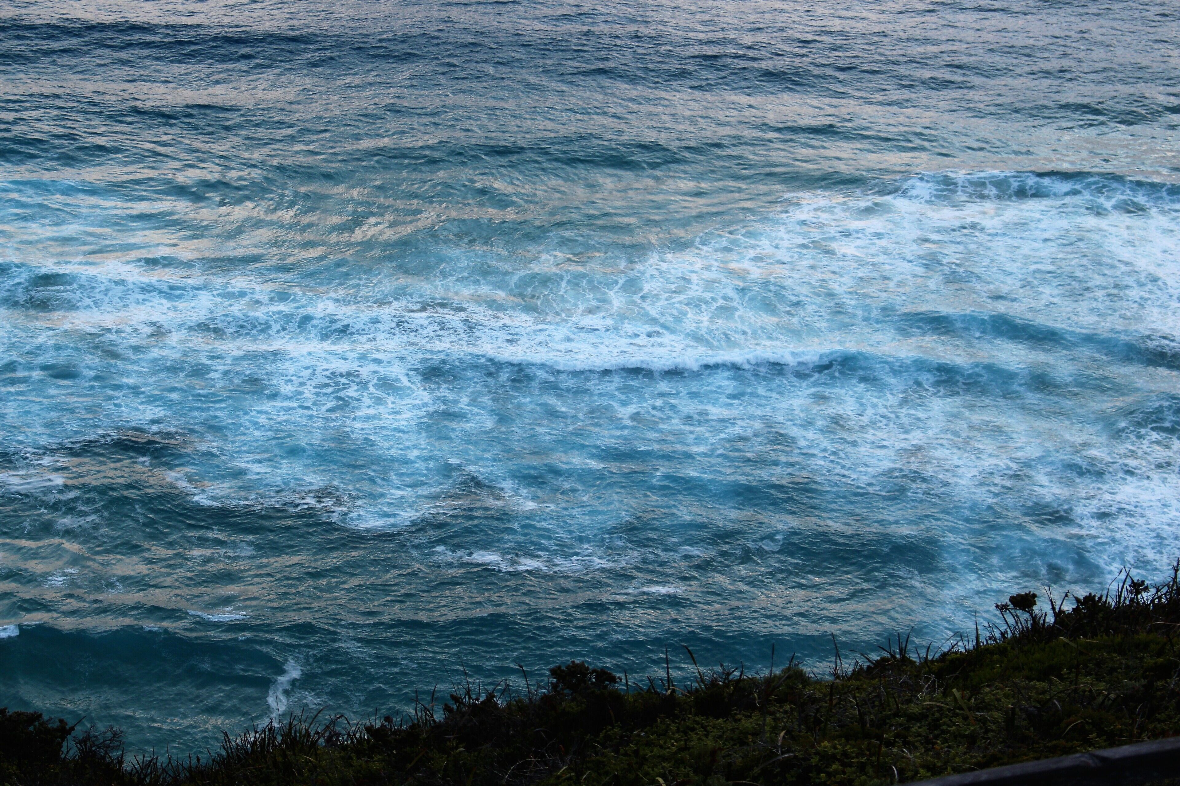 A view of the ocean with waves crashing onto a rocky shore.