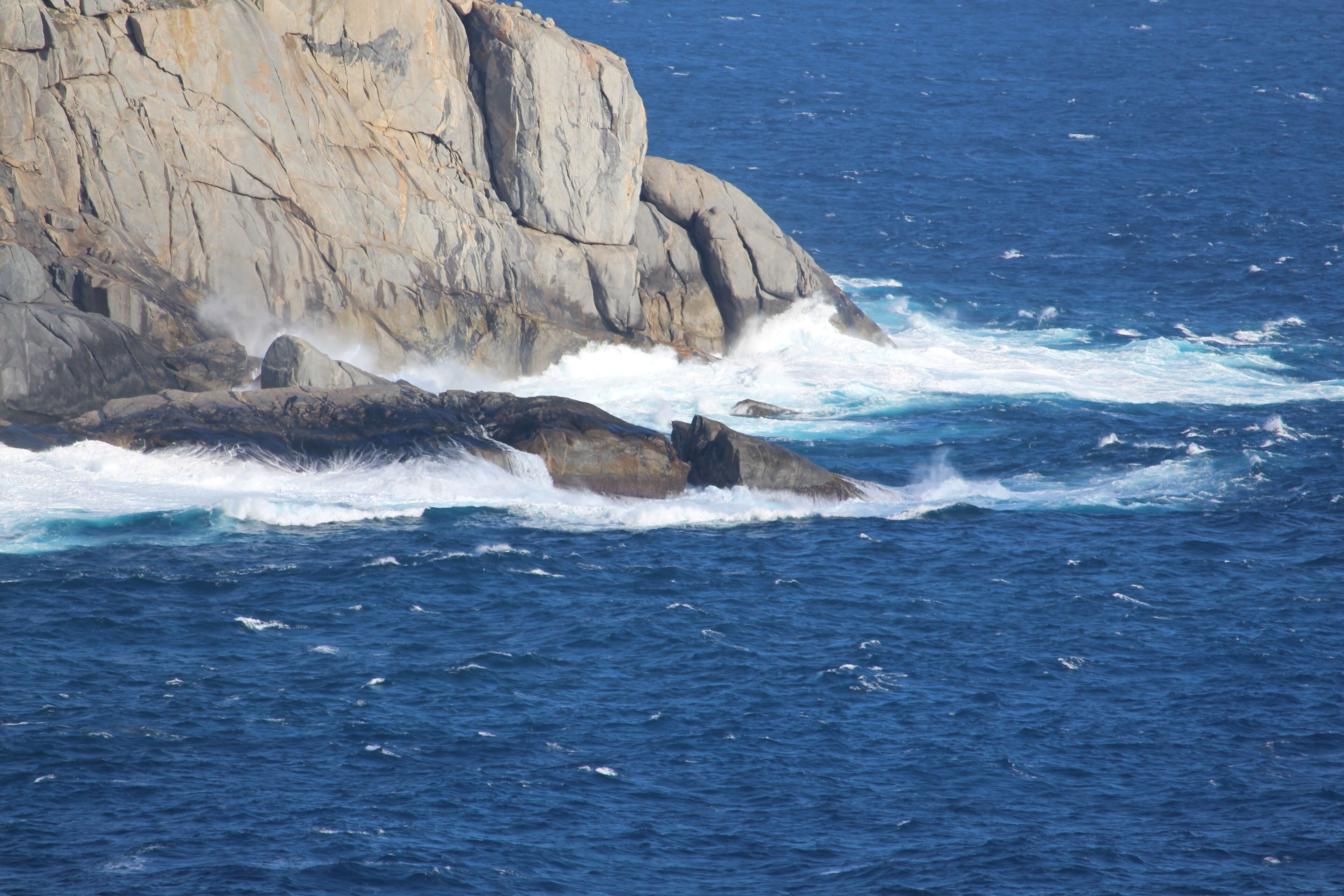 Une côte rocheuse où les vagues s’écrasent contre les rochers.