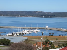 Un puerto deportivo con varias embarcaciones amarradas, un faro y una escasa ola rompeolas.