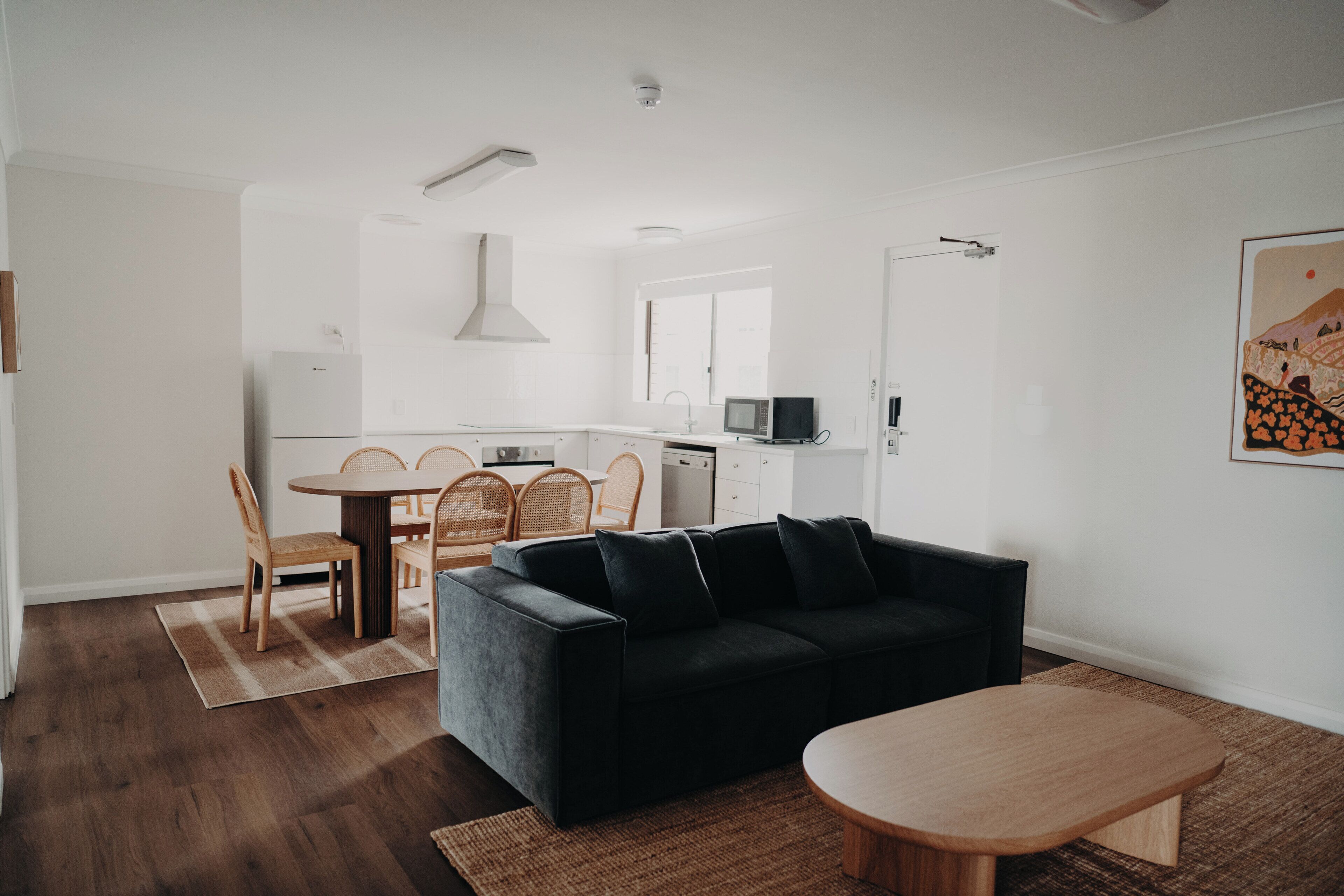 Un espacio moderno para vivir con un sofá negro, una mesa de comedor de madera y sillas.