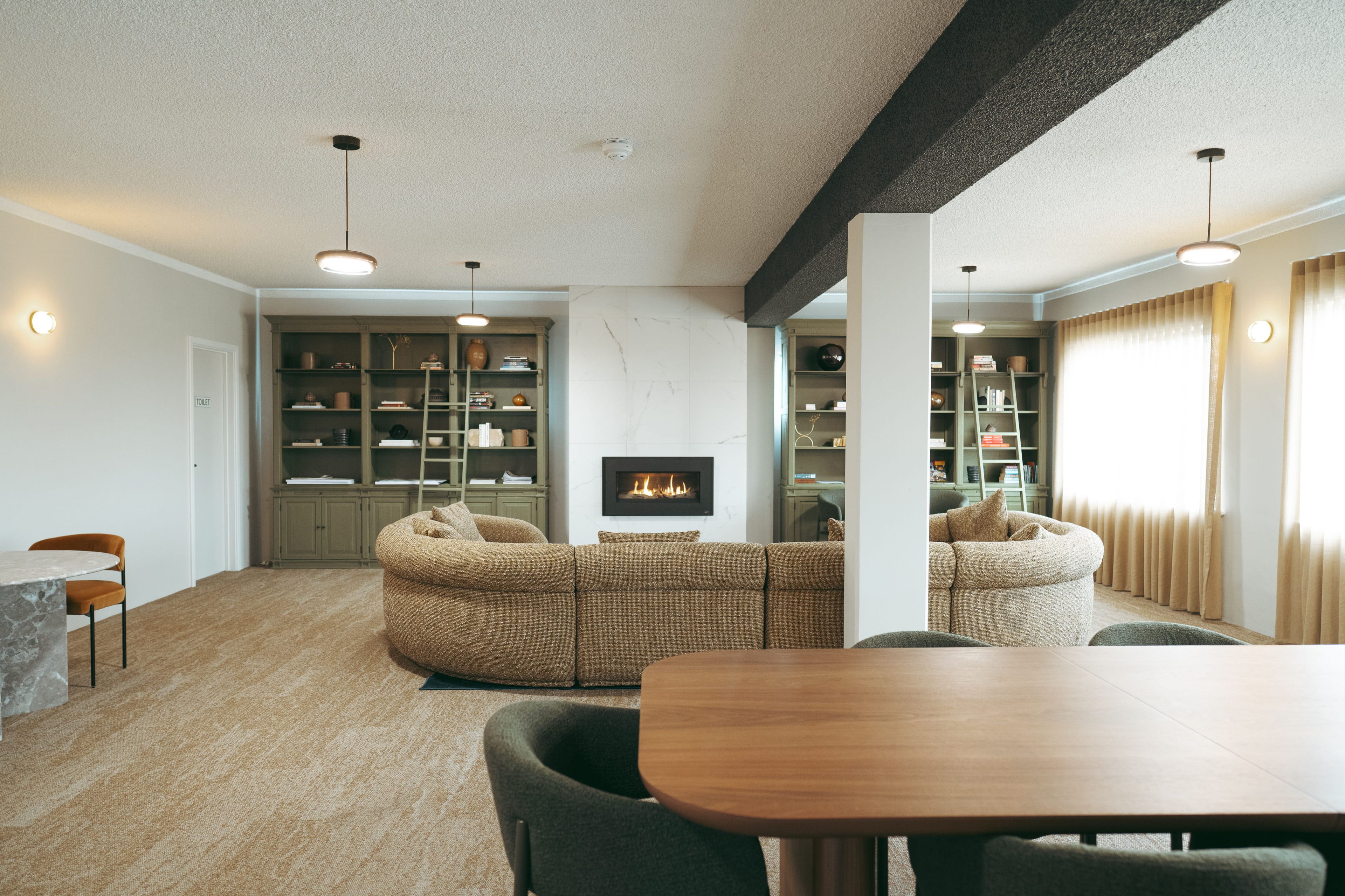 Una sala de estar moderna con chimenea, estanterías empotradas y un comedor.