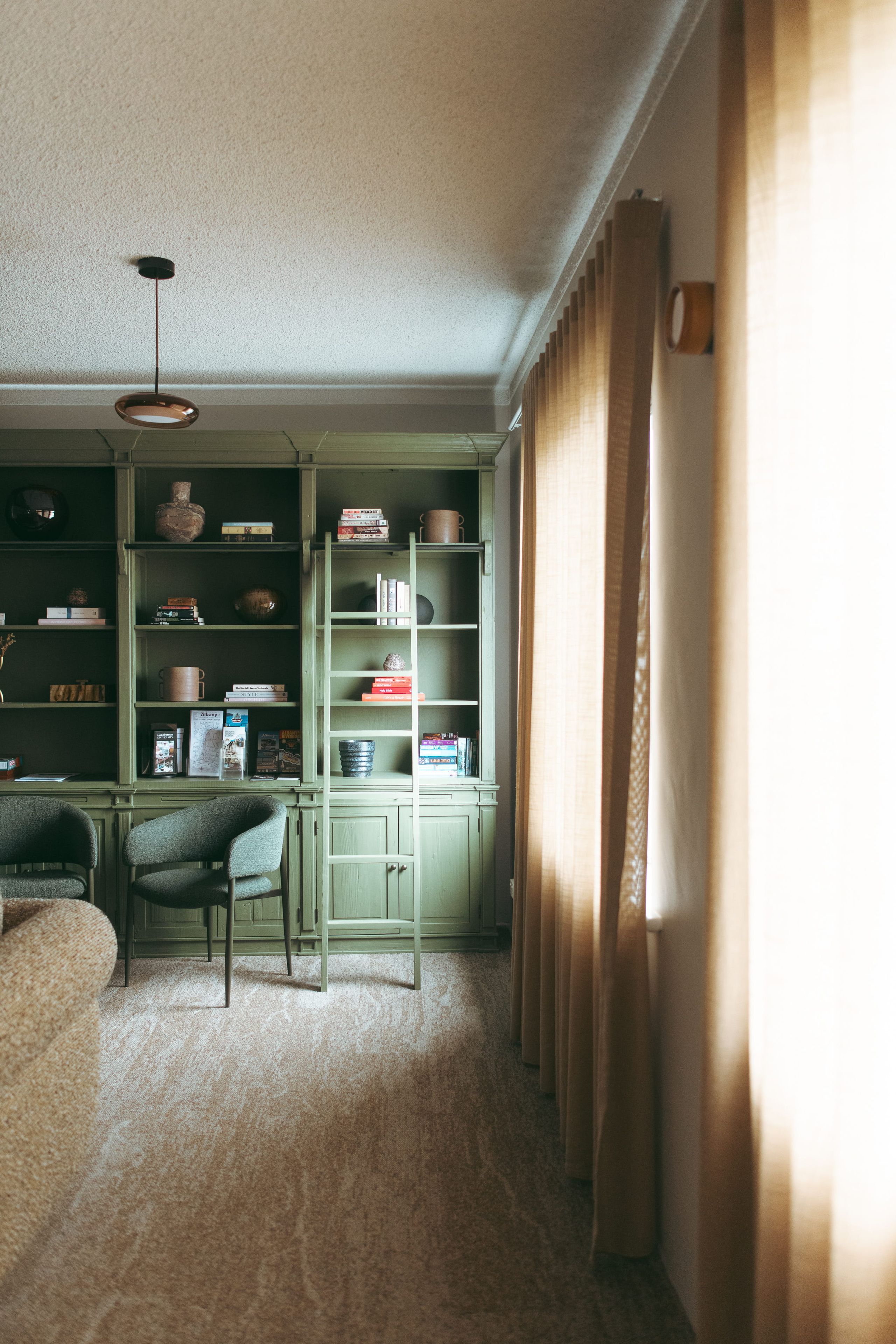 A room with a green bookshelf, a desk, and a chair.