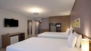 Habitación de hotel con dos camas, televisión, escritorio, armario y espejo.