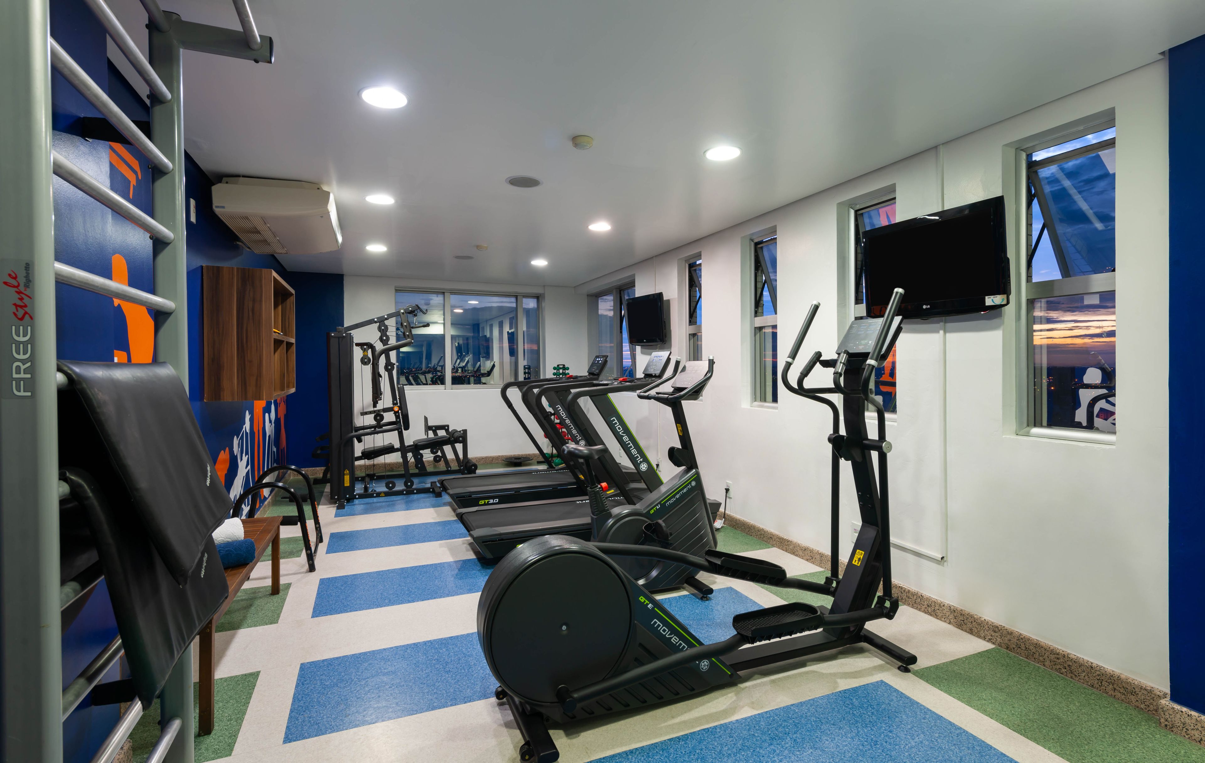 Un gimnasio con cintas de correr, elípticas y equipo de levantamiento de pesas.