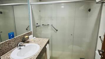 A bathroom with a granite countertop sink, a glass shower enclosure, and a white toilet.