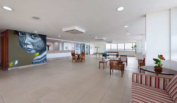 Um hall amplo com balcão de atendimento, área de estar e mesa de bilhar.
