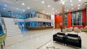 Eine geräumige Lobby mit Treppe, Empfangsbereich und Sitzgelegenheiten.