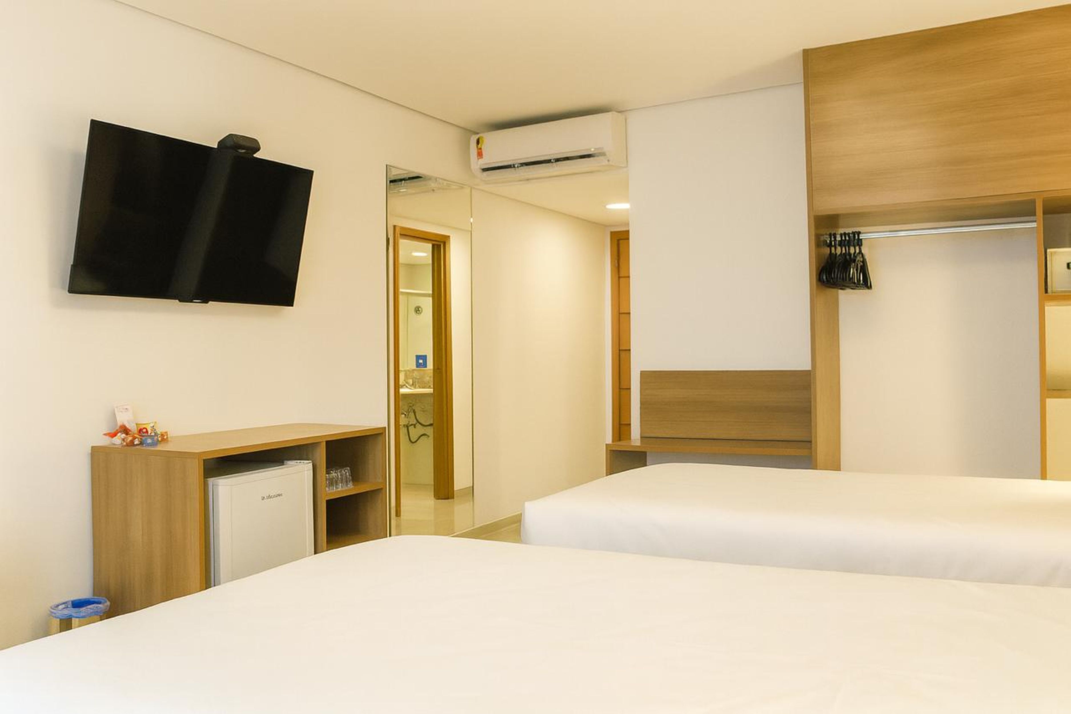 Habitación de hotel con dos camas, un televisor, un escritorio con computadora y un armario.
