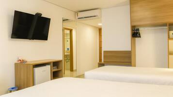 Habitación de hotel con dos camas, un televisor, un escritorio con computadora y un armario.