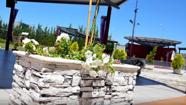 A stone planter with white flowers and a clear blue sky in the background. - Hotel Villa de Benavente (Benavente)