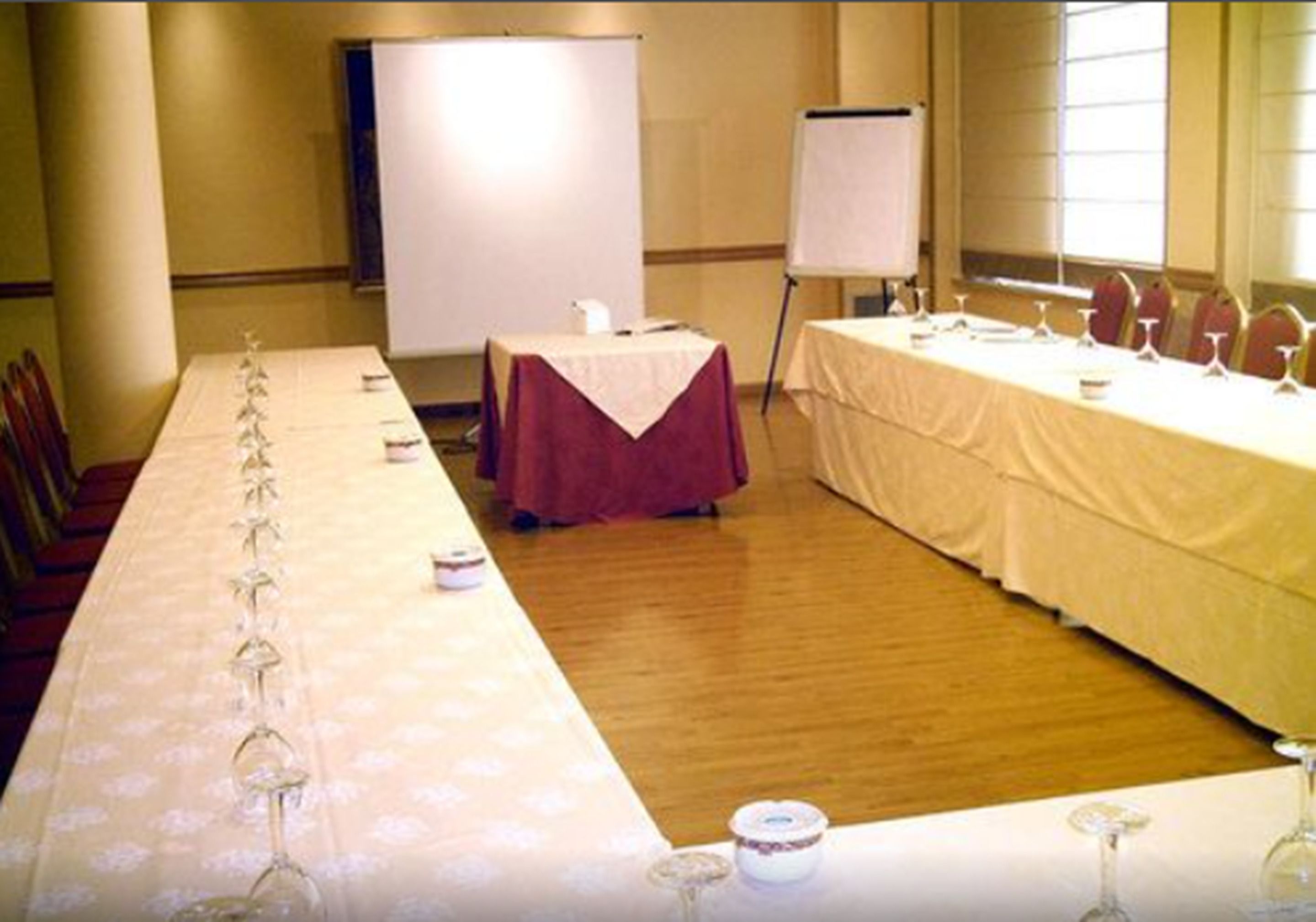 Un salón de conferencias con una larga mesa dispuesta para una reunión, una pizarra y un rotafolio.