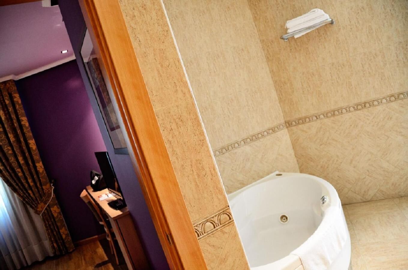 Un baño con bañera, tocador con espejo y un perchero en la pared.