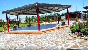 A covered outdoor area with stone flooring, red pillars, and potted plants. - Hotel Villa de Benavente (Benavente)