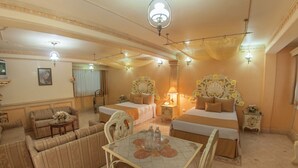 A hotel room with two beds, a sofa set, a dining table, and a chandelier. - Hotel Villa Las Margaritas Plaza Cristal (Xalapa)