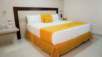 A hotel room with a large bed, white bedding, and a yellow accent.