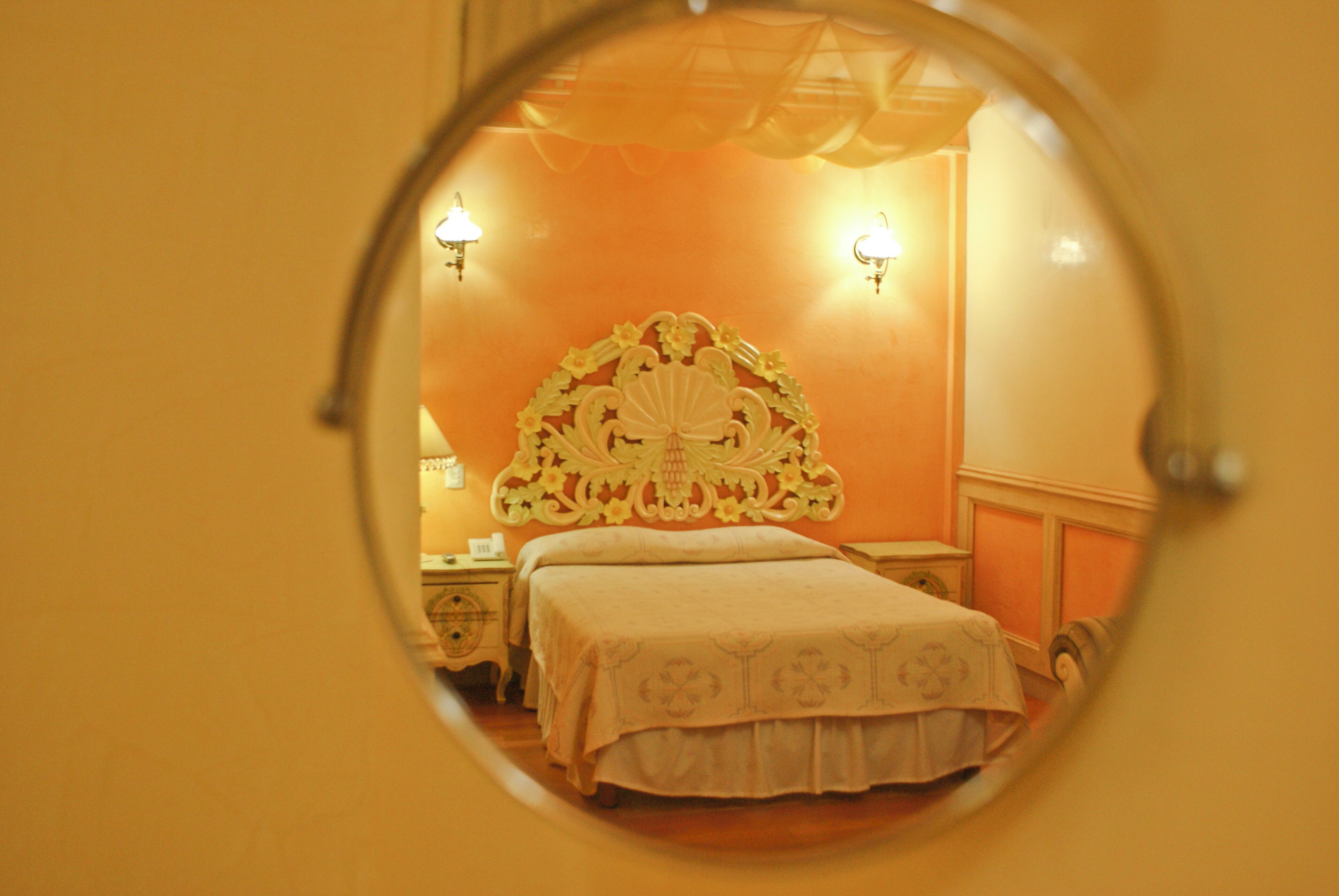A bedroom with a bed, a nightstand, and a wall-mounted lamp.