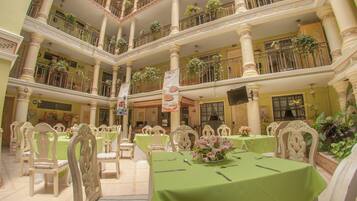 A multi-level atrium with dining tables, chairs, and potted plants.