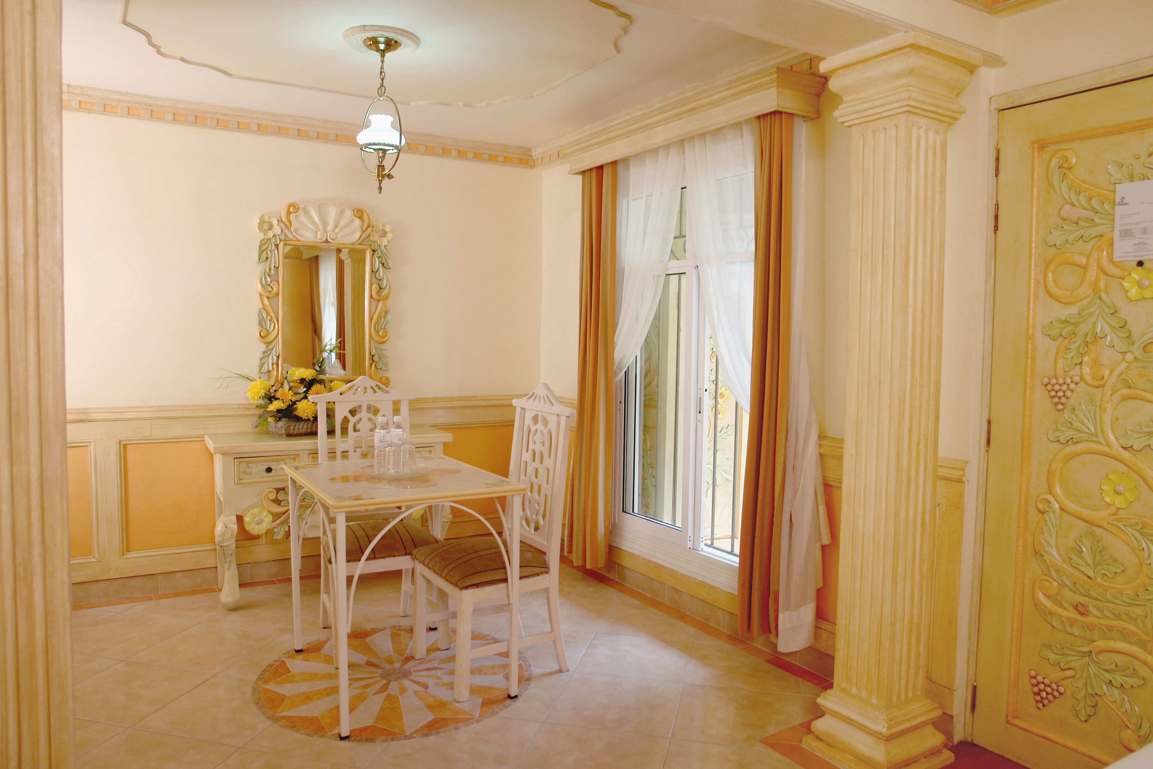 A room with a dining table, chairs, a mirror, and a window with curtains.