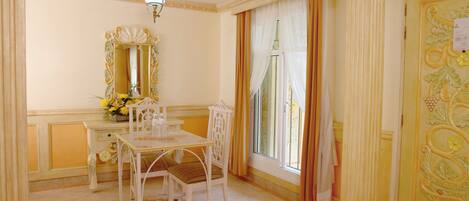 A room with a dining table, chairs, a mirror, and a window with curtains.