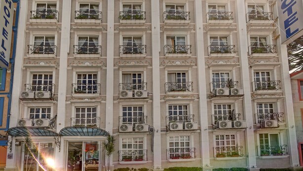 A multi-story hotel with a prominent 'HOTEL' sign above the entrance. - Hotel Villa Las Margaritas Plaza Cristal (Xalapa)