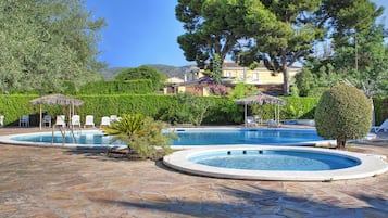 Una piscina al aire libre de temporada, sombrillas, tumbonas