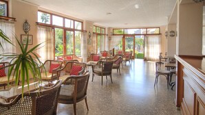 Een ruime kamer met rieten meubels, grote ramen en een gepolijste vloer.