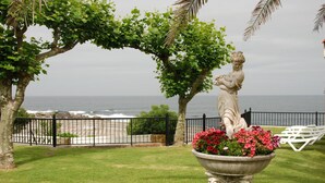 Un jardín ajardinado con una estatua, una maceta y vistas al océano.