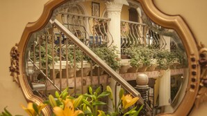Ein Spiegel, der eine Treppe mit aufwendiger Geländer und Topfpflanzen reflektiert.
