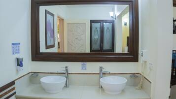 Casa de banho com duas pias, um espelho grande e uma moldura de azulejos decorativa.