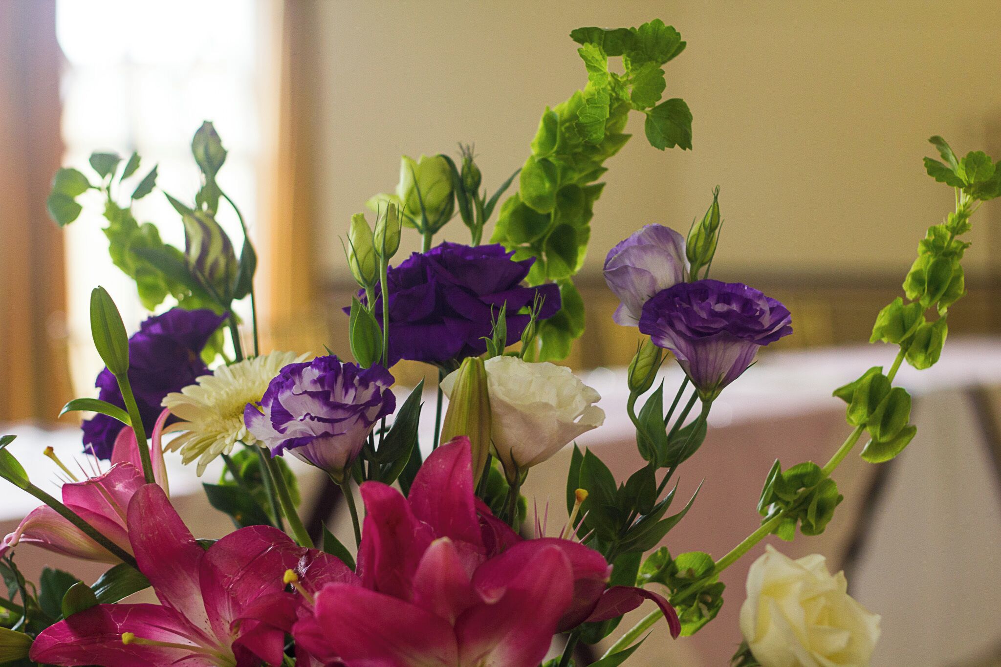Um buquê de flores com diversas cores, incluindo roxo, branco e rosa.