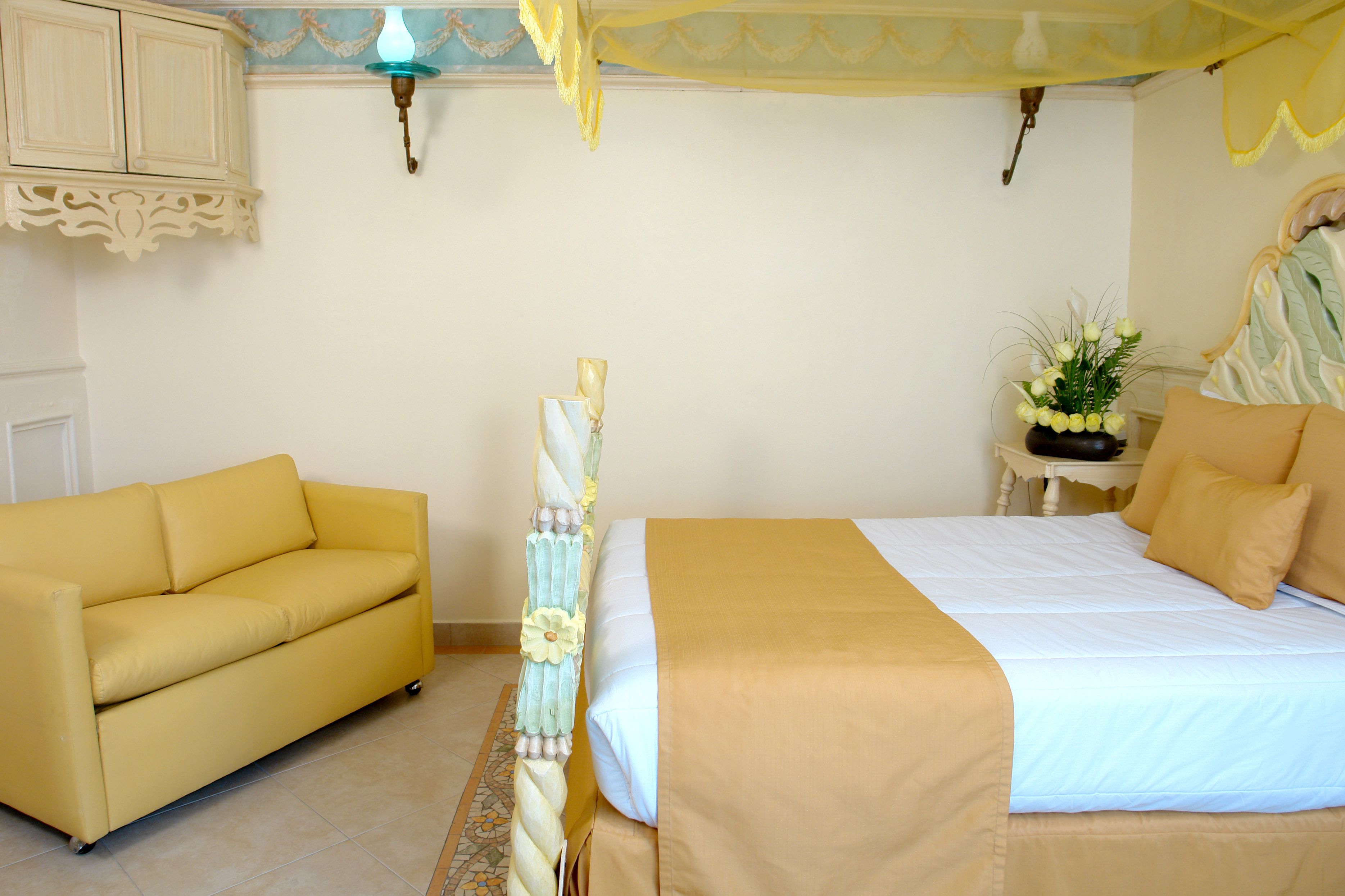 Un dormitorio con cama, sofá, mesita de noche y lámpara de pared.