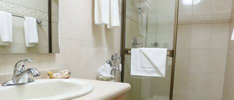 A bathroom with a sink, mirror, toilet, and glass shower enclosure.