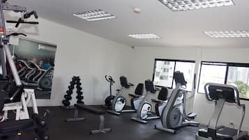 Un gimnasio con cintas de correr, elípticas y máquinas de pesas.
