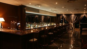 A bar area with a long counter, multiple stools, and a well-lit ambiance. - Hotel Yokohama Camelot Japan (Yokohama)