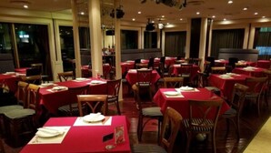 A restaurant with multiple tables covered in red tablecloths, wooden chairs, and a modern interior design. - Hotel Yokohama Camelot Japan (Yokohama)