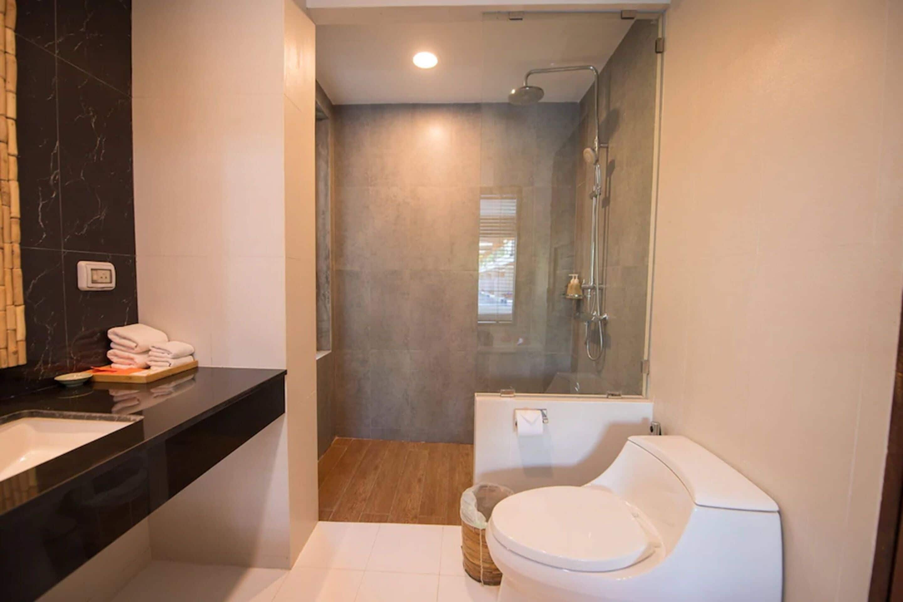 A modern bathroom with a black marble sink, a toilet, and a glass-enclosed shower.