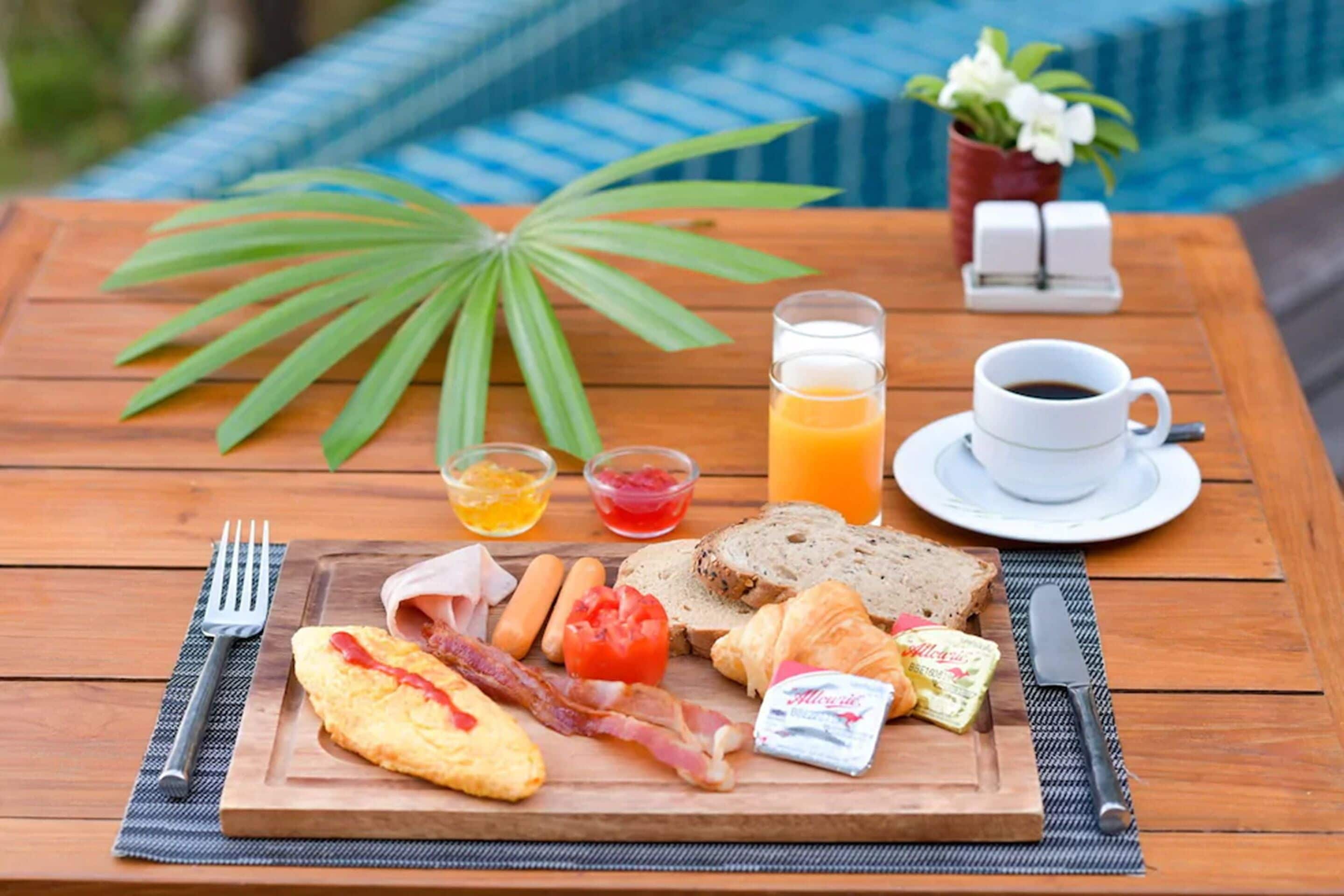 A breakfast table with eggs, bacon, toast, bread, butter, cheese, and a cup of coffee.