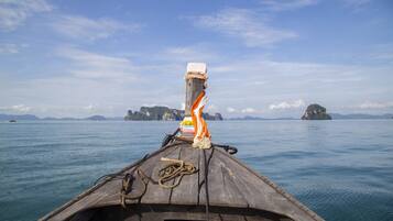 A wooden boat with ropes and a flag, sailing on calm waters with distant islands.