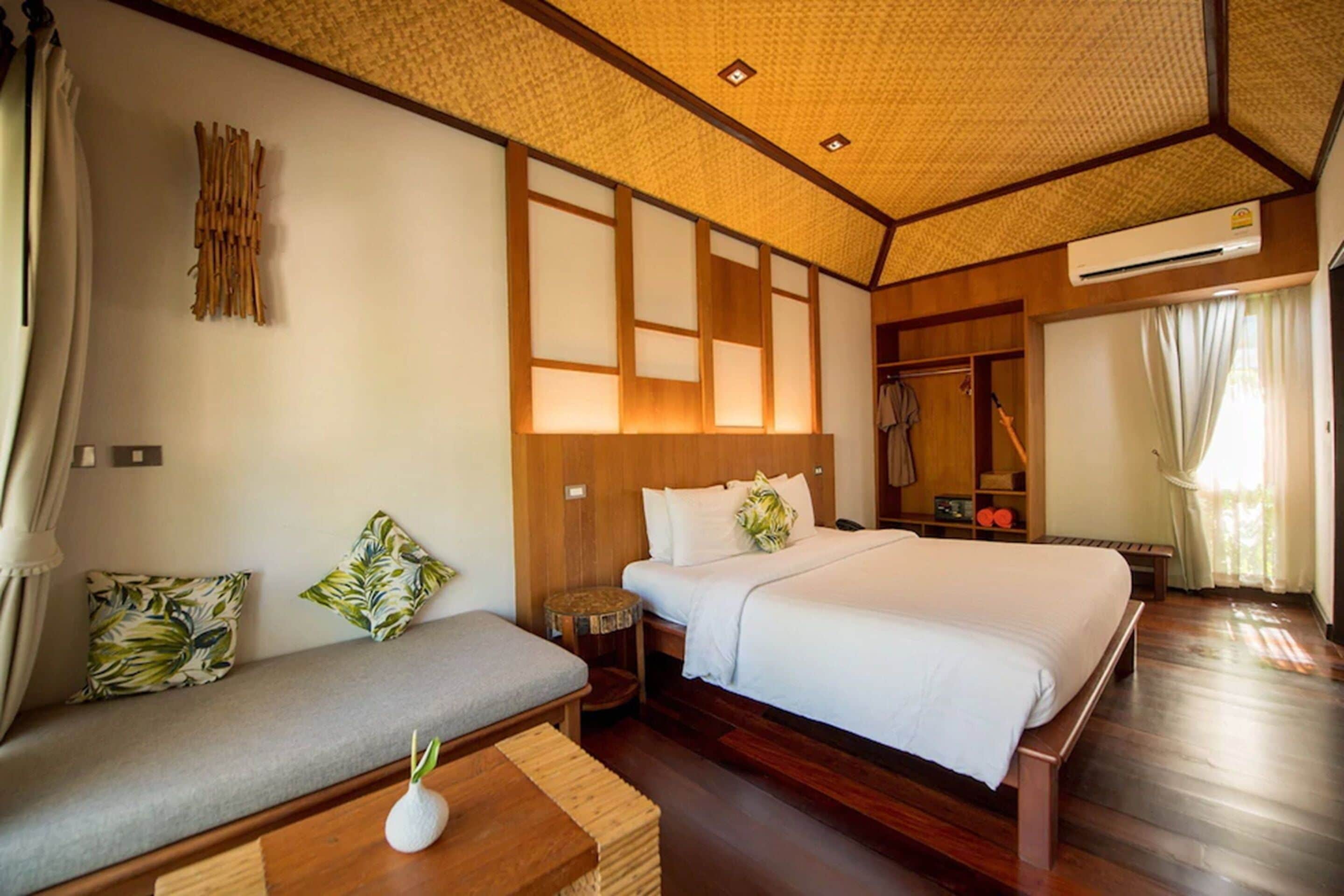 A hotel room with a large bed, a sofa, a small table, and a wardrobe.