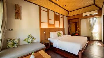 A hotel room with a large bed, a sofa, a small table, and a wardrobe.