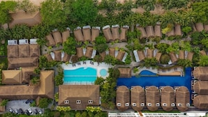 Vista aérea de un resort con playa, piscina y varias cabañas.