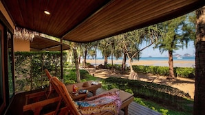 Terraza de madera con mesa y sillas con vista a una playa.