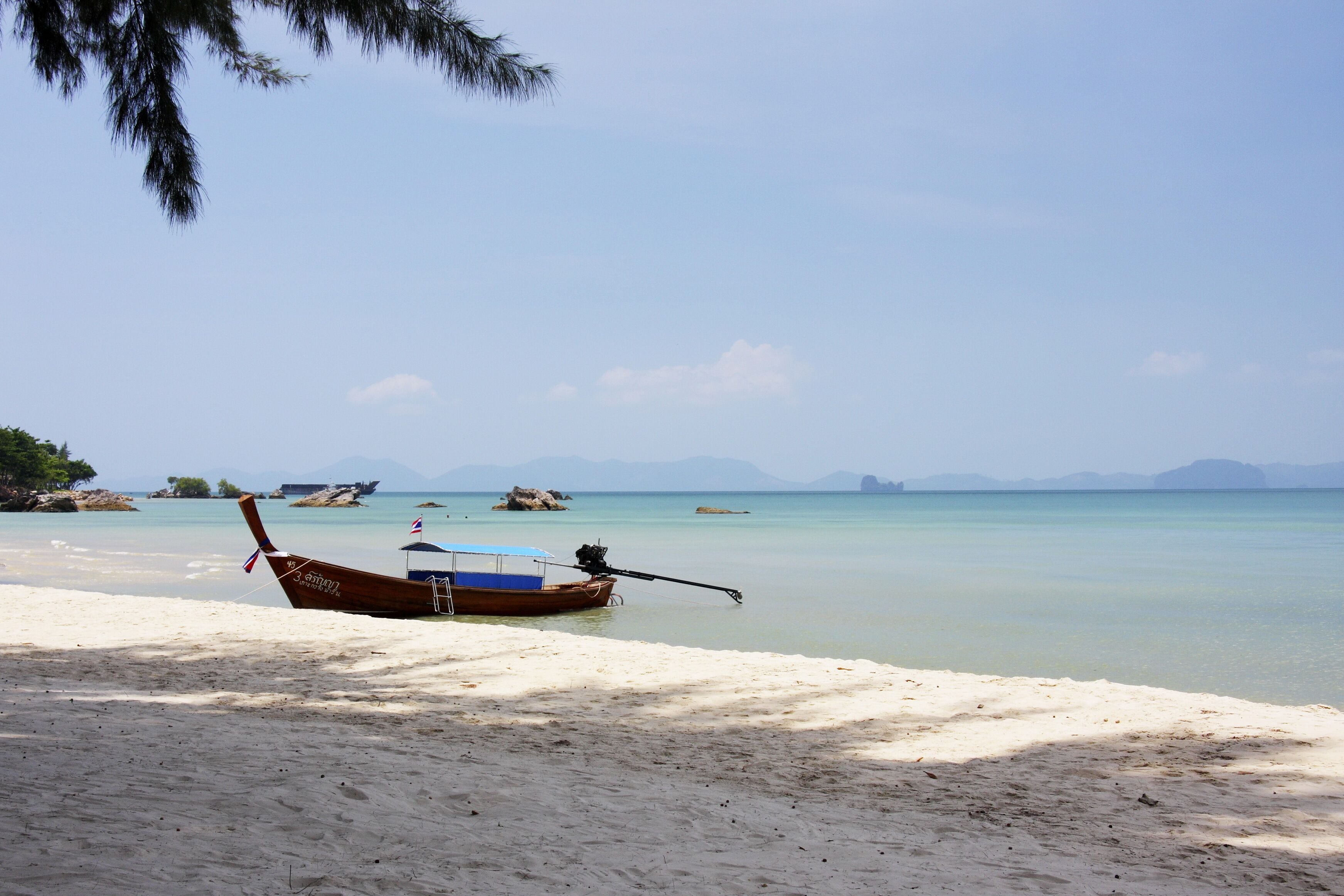 Une plage avec un bateau en bois et une vue dégagée sur la mer.